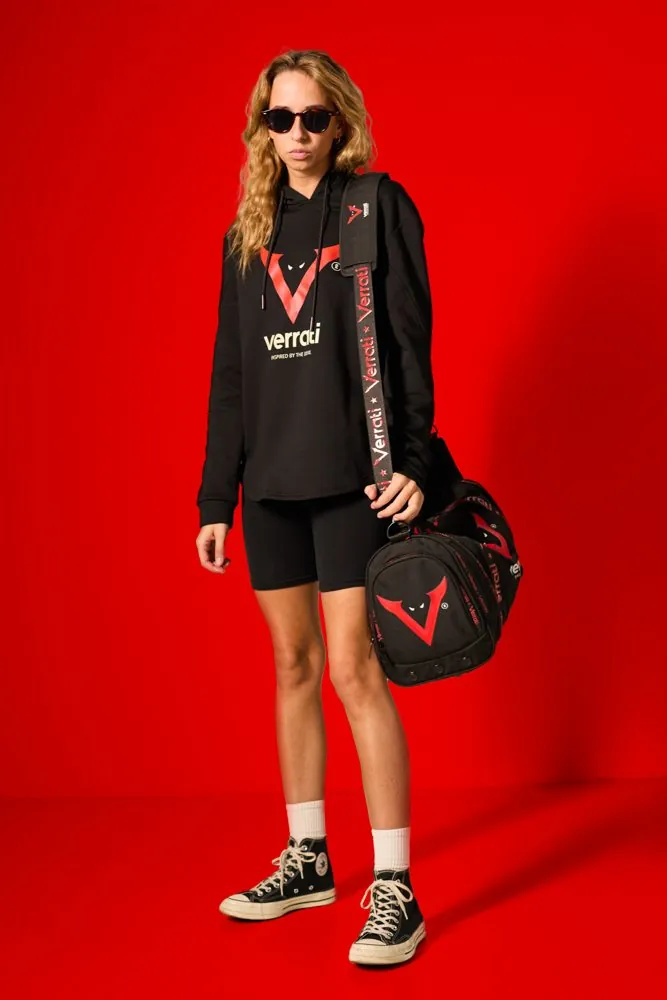 Model in the Verrati hoodie and shorts carrying the branded duffel, on a red backdrop